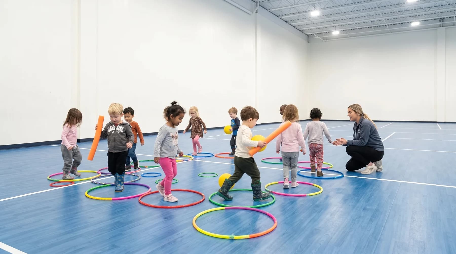 A toddler moving through an obstacle setup with an educator close by in the Playbox gym.
